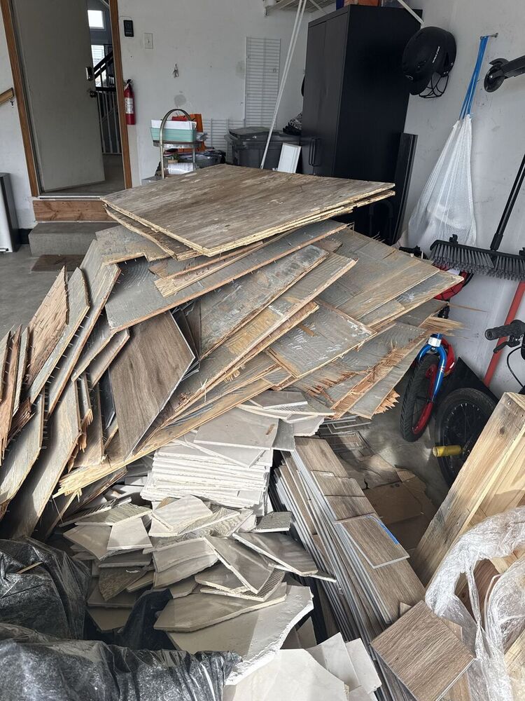 Garage full of scrap wood and flooring debris before a 708 JUNK garage cleanout in the Orland Park area
